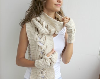 May include: A woman wearing a white knitted scarf with a unique braided design and matching fingerless gloves. The scarf has long fringe at the ends.