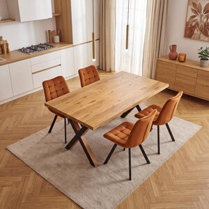 Op de afbeelding: Een rechthoekige eettafel met een lichtbruin houten blad en zwarte metalen X-vormige poten, vergezeld door vier oranje fluwelen stoelen met een gewatteerd vierkant patroon op de rugleuning en zitting, op dunne zwarte metalen poten.