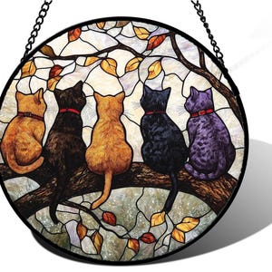 Puede incluir: Vidriera redonda con cinco gatos de diferentes colores posados en una rama. Cada gato lleva un collar rojo. El fondo es una mezcla de blanco y verde claro, con hojas otoñales.