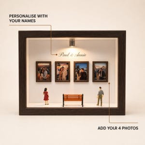 May include: A dark wood shadow box display featuring four framed photos on a white wall, a miniature orange bench, and two small figurines. The text "Paul & Annie" is printed above the photos, with labels "PERSONALISE WITH YOUR NAMES" and "ADD YOUR 4 PHOTOS".