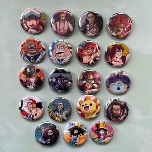May include: A collection of twenty round pinback buttons featuring colorful anime character illustrations. The buttons showcase various characters with detailed facial expressions and vibrant outfits. The buttons are arranged on a light green surface.