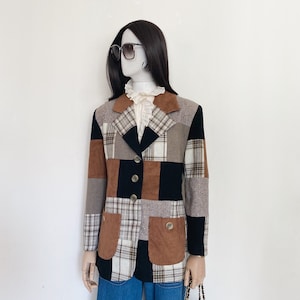 May include: A brown, black and white patchwork blazer with a corduroy collar and pockets. The blazer has a button closure and is worn on a mannequin.