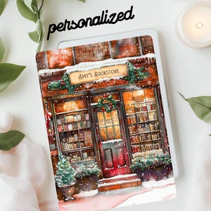 May include: A personalized tablet case featuring a watercolor illustration of "Amy's Bookstore" in a winter scene. The design includes a snow-covered storefront with a Christmas wreath and a small Christmas tree. The word "personalized" is written above the tablet.