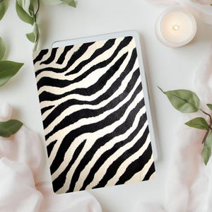 Op de afbeelding: Een laptop-huid met zebraprint in zwart en wit. De huid is gemaakt van een duurzaam materiaal en is ontworpen om uw laptop te beschermen tegen krassen en slijtage.