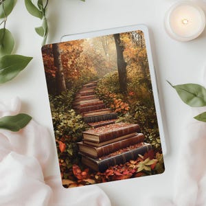 May include: A stack of old books arranged as steps leading up into a forest. The books are covered in autumn leaves and the forest is filled with fall foliage.