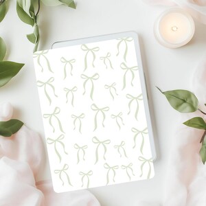 May include: A white background with a repeating pattern of light green bows. The bows are all facing the same direction and are arranged in a staggered pattern.