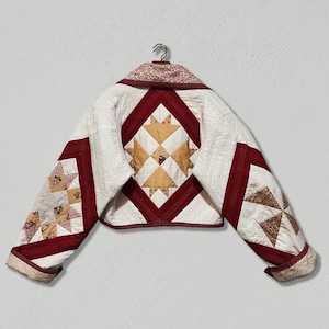 May include: A white quilted jacket with red and brown patchwork details. The jacket has a diamond-shaped pattern on the back and a floral print on the collar.