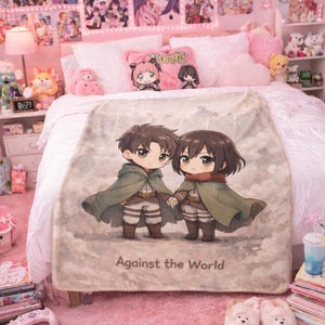 Op de afbeelding: Een beige deken met een anime-stijl illustratie van twee hand in hand lopende personages, gekleed in groene capes en beige broeken. De tekst "Against the World" staat onderaan gedrukt. De deken ligt op een bed met roze decoratie.