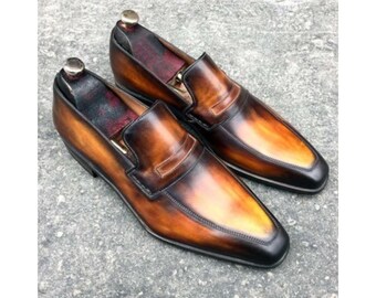 May include: A pair of brown leather loafers with a gradient effect, transitioning from dark brown to a lighter tan. The shoes have a classic penny loafer design with a rounded toe and a polished finish. The interior is lined with a burgundy material.