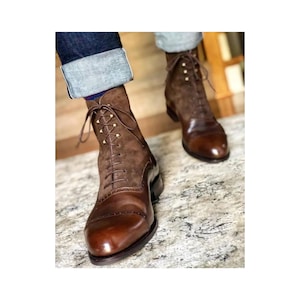 May include: Brown leather and suede lace-up boots. The boots have a cap toe design and are laced up the front with brown laces. The upper portion of the boot is a dark brown suede, while the lower portion is a polished brown leather.