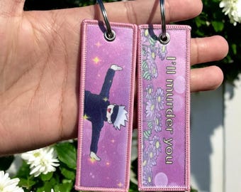 May include: Two rectangular keychains with silver key rings. One keychain features an anime character in a black outfit with a white mask, set against a purple starry background. The other keychain has the text "I'll murder you" with a floral border.