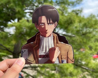 May include: A sticker featuring a character from the anime Attack on Titan. The character has brown hair, brown eyes, and is wearing a brown jacket with a white scarf. The character is looking to the right and has a serious expression on their face.