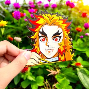 May include: A sticker featuring a cartoon character with red and yellow hair, wearing a blue shirt and eating noodles with chopsticks. The character has red eyes and a black and white face.