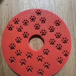 Peut inclure: Insert de gamelle pour animaux de compagnie rouge, de forme circulaire, avec un trou central et de nombreuses découpes en forme de pattes. L'insert est conçu pour ralentir l'alimentation et est fait d'un matériau texturé.
