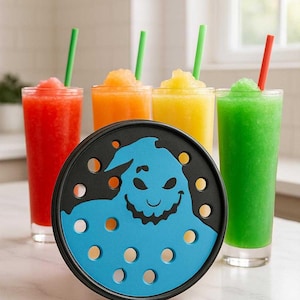 Peut inclure: Un dessous de verre noir et bleu avec un motif de personnage de dessin animé, un bord noir et des découpes circulaires. Quatre grands verres de granités colorés avec des pailles sont en arrière-plan : rouge, orange, jaune et vert.