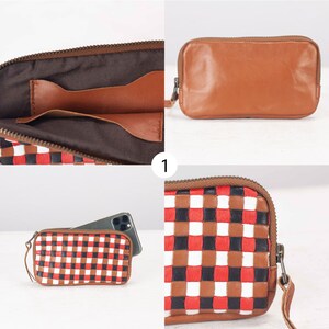 May include: A brown leather wallet with a checkered pattern in red, white, and black. The wallet has a zipper closure and a strap.