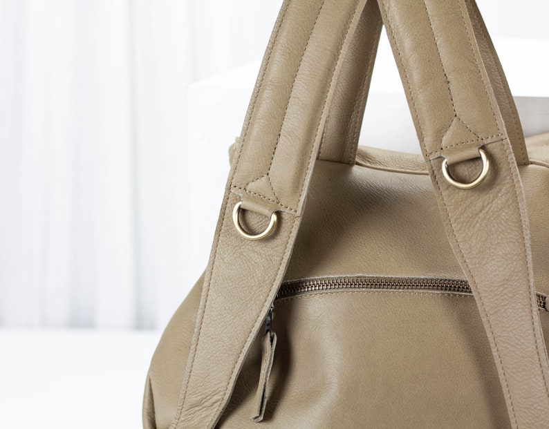 May include: A tan leather backpack with two adjustable straps and gold metal hardware. The straps have a quilted design.