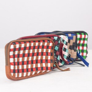 May include: Five woven leather zippered pouches in different colors and patterns. The pouches are lined up in a row, with the red, white, and brown pouch in the front.