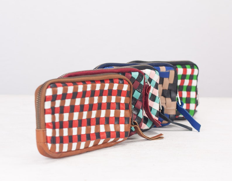 May include: Five woven leather zippered pouches in different colors and patterns. The pouches are lined up in a row, with the red, white, and brown pouch in the front.