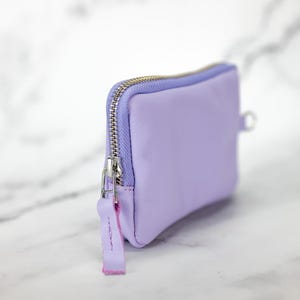 May include: A small lavender zippered pouch with a silver zipper and a pink zipper pull.