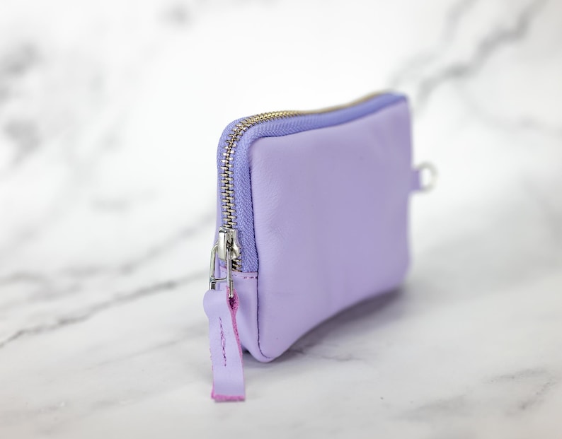 May include: A small lavender zippered pouch with a silver zipper and a pink zipper pull.