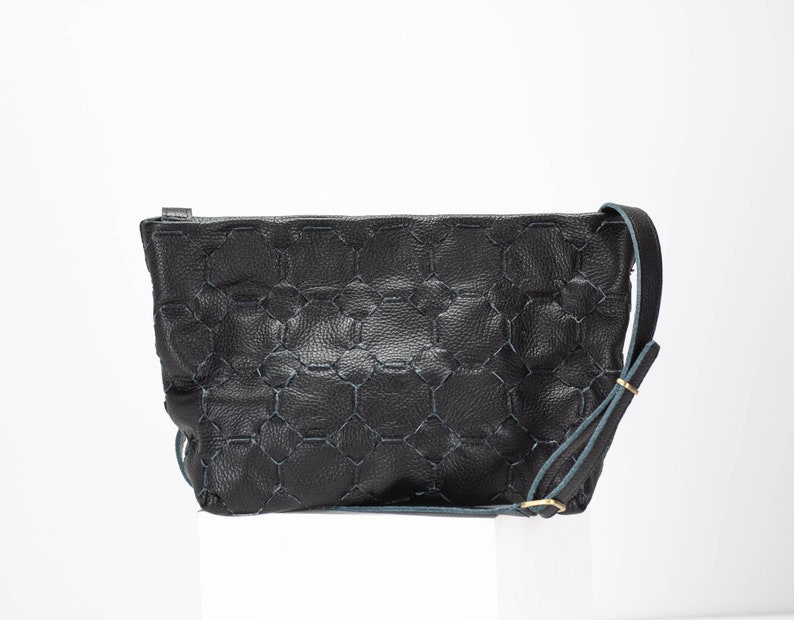 May include: Black leather crossbody bag with a geometric pattern and a blue strap.