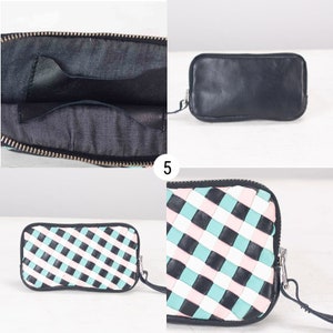 May include: A black leather clutch with a zipper closure. The clutch has a woven pattern with black, white, and light blue stripes. The clutch is shown open, revealing a black fabric interior with a zippered pocket.