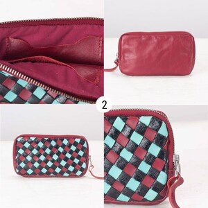 May include: A red leather wallet with a woven pattern of black and turquoise squares. The wallet has a zipper closure and a small strap.