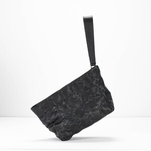 May include: A black quilted leather clutch with a top handle.