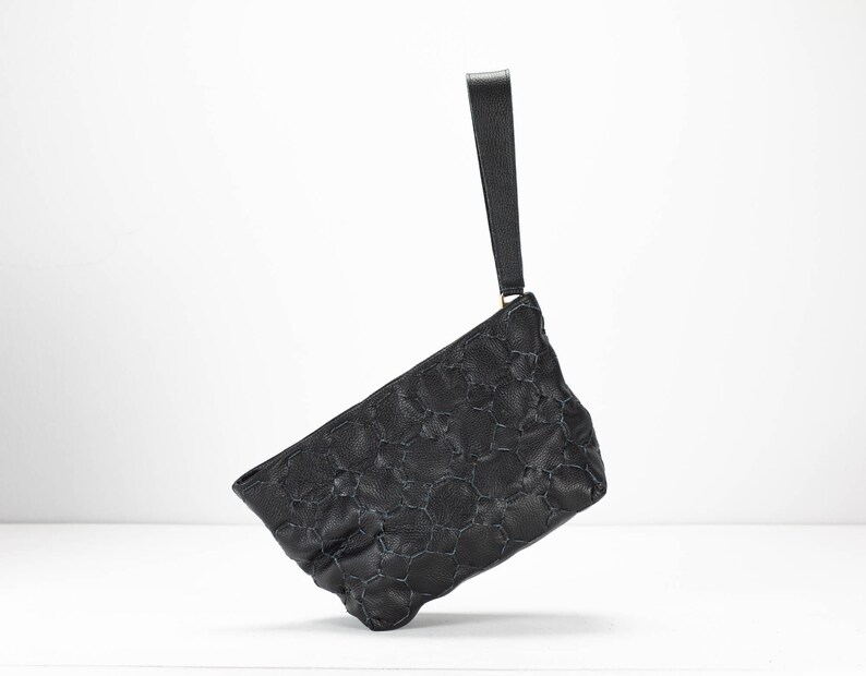 May include: A black quilted leather clutch with a top handle.