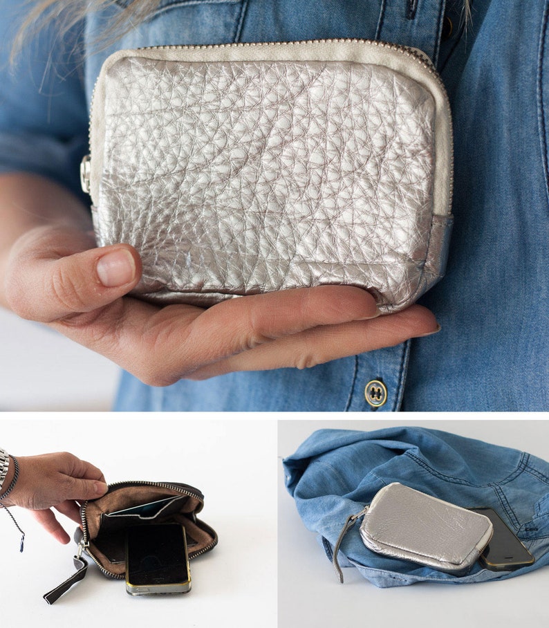 May include: A silver leather zippered pouch with a textured surface. The pouch is open and shows a black phone and a credit card inside.