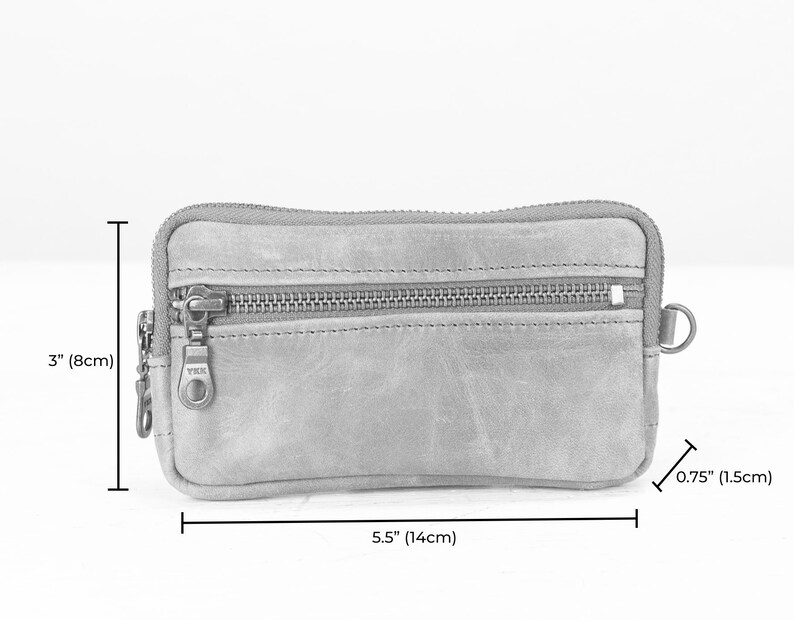 May include: A brown leather zippered pouch with a YKK zipper pull. The pouch measures 5.5 inches wide by 3 inches tall and 0.75 inches deep.