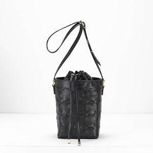 May include: Black leather bucket bag with a gold drawstring closure and a gold chain strap.