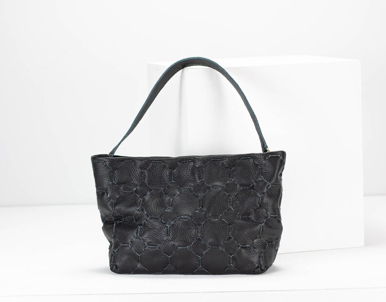 May include: A black leather handbag with a blue stitched pattern and a single top handle.