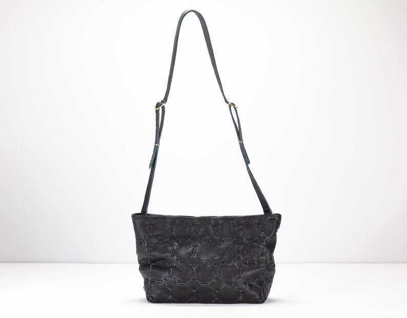 May include: A black leather shoulder bag with a quilted pattern and a gold-toned buckle.