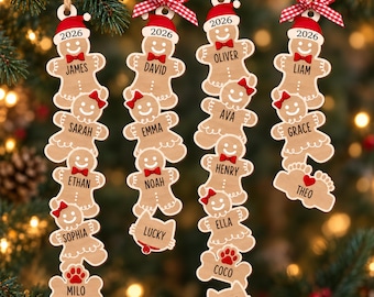 Puede incluir: Cuatro adornos navideños verticales de madera con forma de hombre de jengibre, cada uno con un lazo de cuadros rojo y blanco y un gorro de Papá Noel con el año 2026. Las figuras incluyen varios nombres, huellas y formas de hueso.