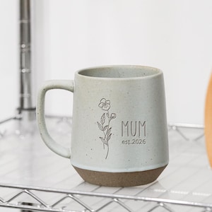 May include: A set of three ceramic mugs with a speckled, matte finish. Each mug features a different color: light blue, cream, and gray. The mugs have a simple, modern design and a comfortable handle.