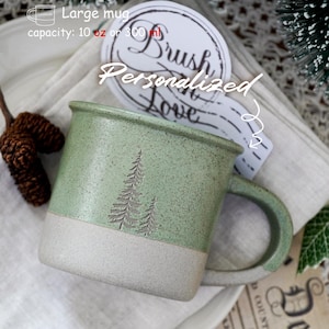 Puede incluir: Una taza grande de cerámica verde con base y asa de color gris claro. La taza tiene una capacidad de 300 ml. Dos pinos grabados decoran el frente. La taza está etiquetada como "Personalizado" y "Brush Love".