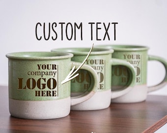May include: Three green ceramic mugs with white rims. The mugs have a brown text design that says "Your company logo here" on one mug and "Your company logo here" on the other two mugs.