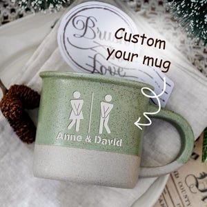 May include: A green and white ceramic mug with a handle. The mug features a design of stick figures and the names "Anne & David." The text "Custom your mug" is also visible.