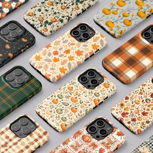 Op de afbeelding: Een collectie smartphonehoesjes met diverse herfstthema-patronen, waaronder oranje pompoenen, kleurrijke herfstbladeren, ruitpatronen en geblokte prints. Elk hoesje is voorzien van een camera-uitsparing en een beschermende behuizing.