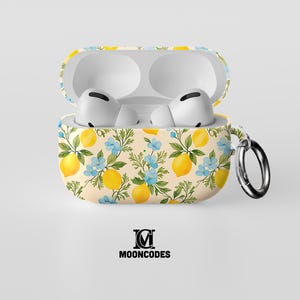 Puede incluir: Estuche abierto para AirPods Pro con un estampado de limones y flores. La funda es de color crema con limones amarillos, flores azules y hojas verdes. La funda tiene un anillo metálico plateado. Los AirPods son blancos.