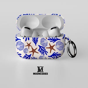 May include: White AirPod case with a blue and brown seashell pattern, open to reveal white earbuds. The case has a silver ring and the text "MOONCODES" in black.