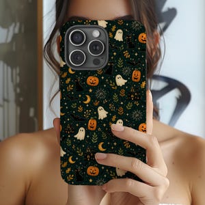 Puede incluir: Una funda para smartphone de color verde oscuro con un patrón repetitivo de Halloween que incluye calabazas naranjas, fantasmas blancos, gatos negros, murciélagos, lunas crecientes, telarañas y pequeñas casas encantadas.