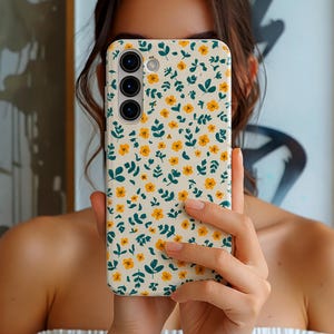 Phone case with small yellow wildflowers and green botanical leaves pattern on a light background, aesthetic floral design for Samsung models, slim protective cover.