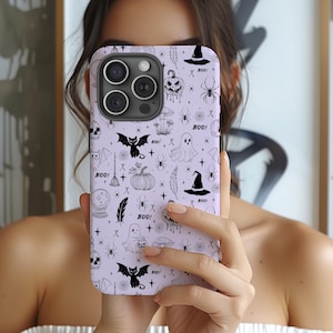 May include: A light purple smartphone case featuring a repeating black line art pattern of Halloween icons including ghosts, bats, skulls, pumpkins, spiders, witch hats, mushrooms, feathers, and the text BOO scattered across the surface.