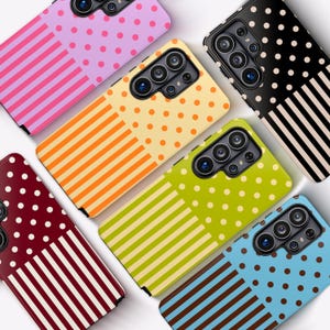 May include: Five rectangular smartphone cases arranged in a cluster, each featuring a split design with polka dots on one half and vertical stripes on the other. The cases come in pink, orange, black, lime green, and light blue color variations.