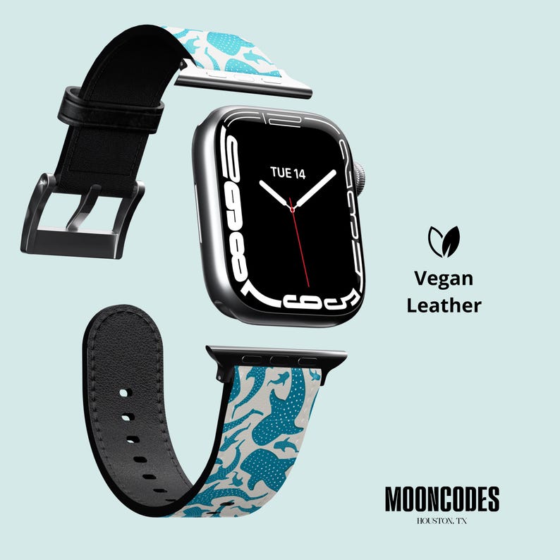 May include: An Apple Watch with a black strap and a patterned vegan leather band featuring blue whale shark illustrations on a light grey background. The watch face displays "TUE 14". The text "Vegan Leather" and "MOONCODES HOUSTON, TX" are also visible.