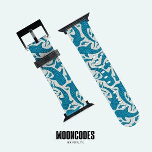 May include: Two-piece watch strap featuring a blue whale shark design on a light beige backdrop. The strap has a black buckle and connectors. The brand name "MOONCODES" and location "HOUSTON, TX" are printed at the bottom.