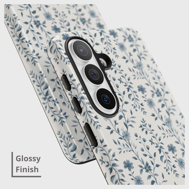 May include: A white phone case with a blue floral pattern and a glossy finish. The case features a camera module with three lenses and side buttons. The text "Glossy Finish" is visible on the left side.